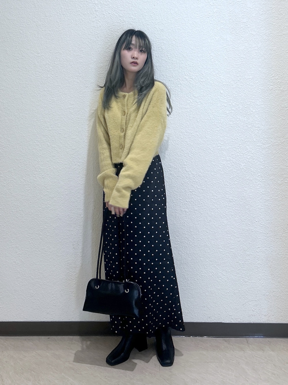 ブラック系のスカート、イエロー系のニット/セーター、ブラック系のショルダーバッグを着用したレディースの秋コーディネートの1枚目の写真