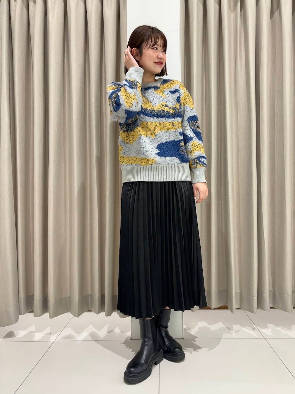 グレー系のニット/セーター、ブラック系のスカートを着用したレディースの秋コーディネートの1枚目の写真