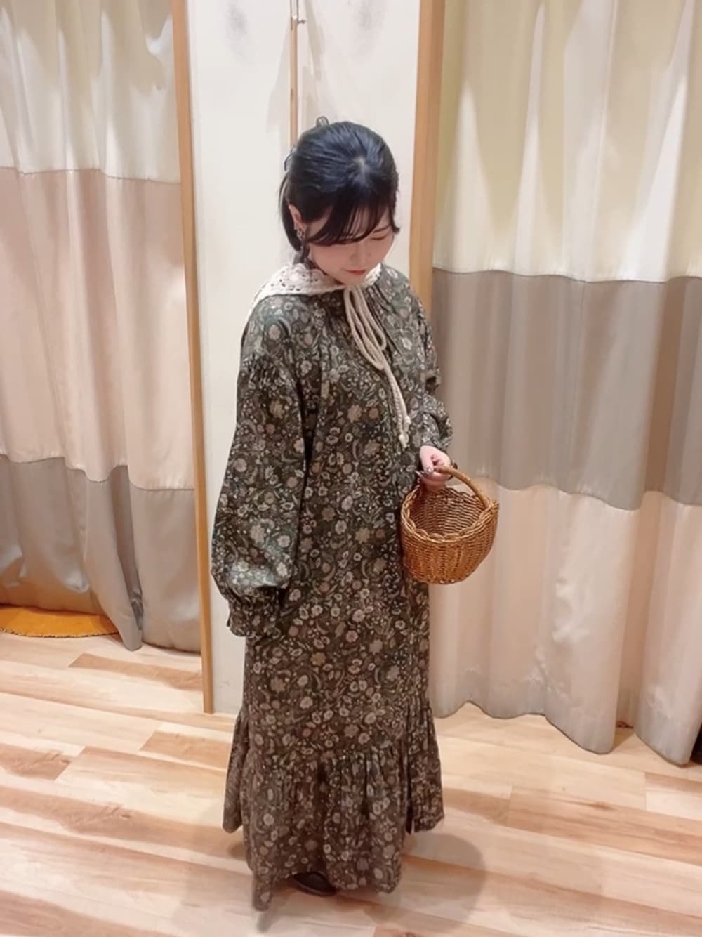 グリーン系のワンピース、ブラウン系のドレスシューズ、ブラウン系のかごバッグを着用したレディースの秋コーディネートの1枚目の写真