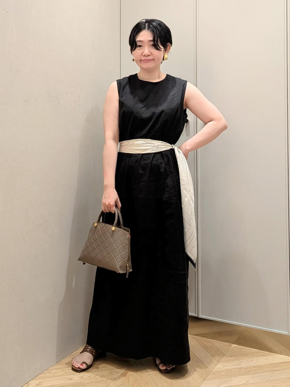 イエロー系のサンダル、ブラック系のワンピース、ホワイト系のバンダナ/スカーフを着用したレディースの夏コーディネートの1枚目の写真