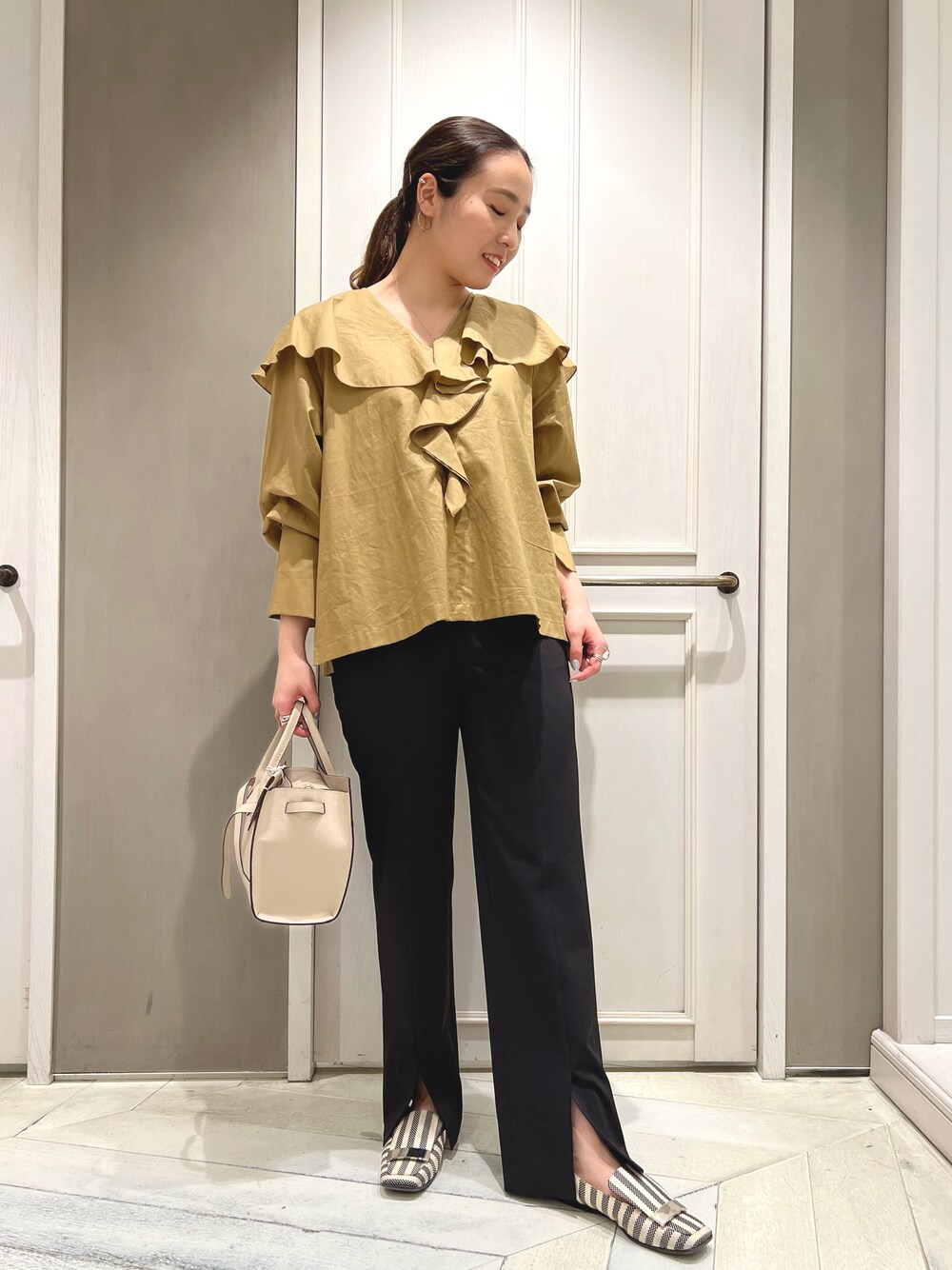 イエロー系のシャツ/ブラウス、ブラック系のその他パンツ、ホワイト系のトートバッグを着用したレディースの春コーディネートの1枚目の写真
