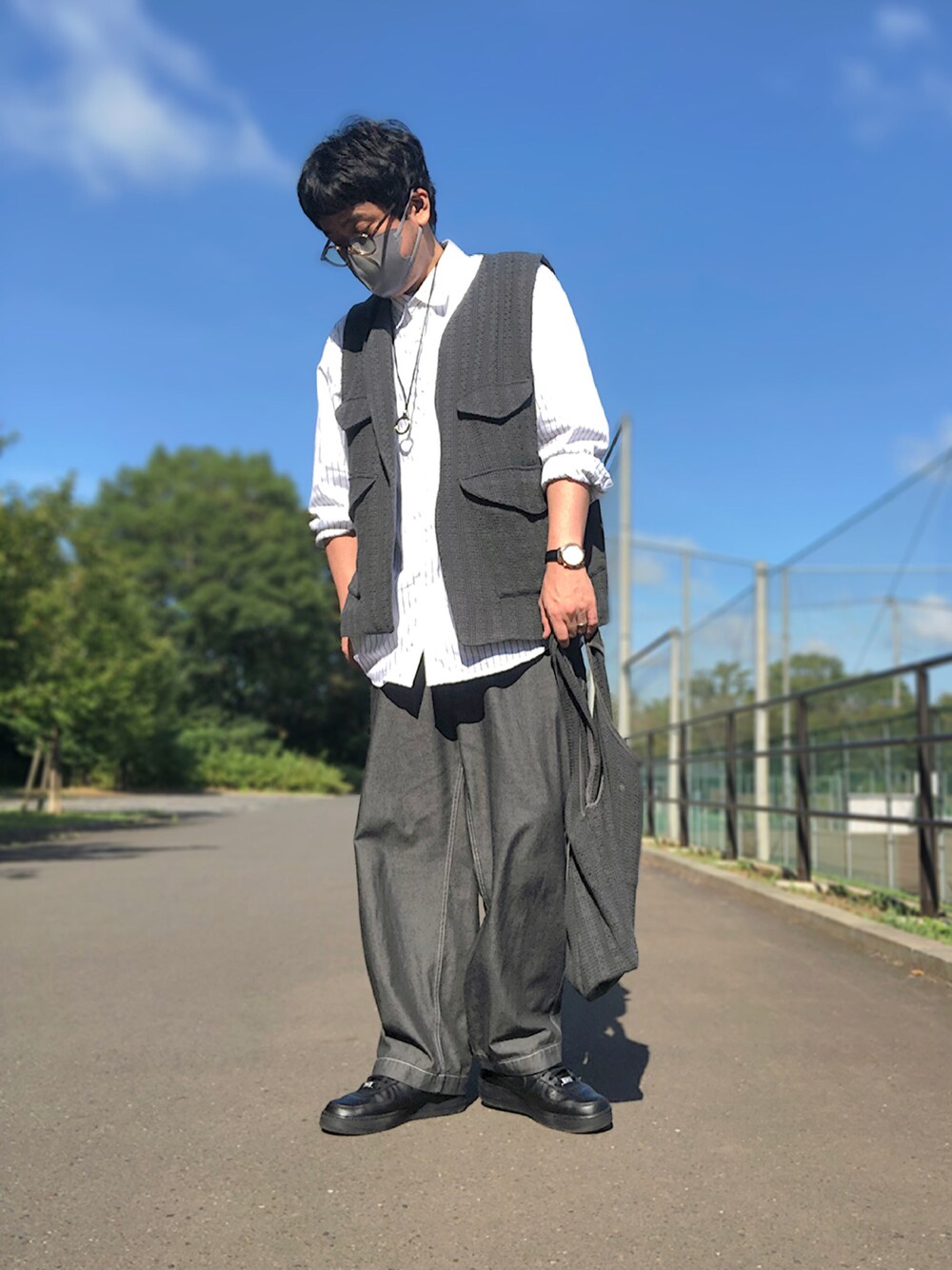 グレー系のベスト、ホワイト系のシャツ/ブラウス、グレー系のトートバッグを着用したメンズの秋コーディネートの1枚目の写真