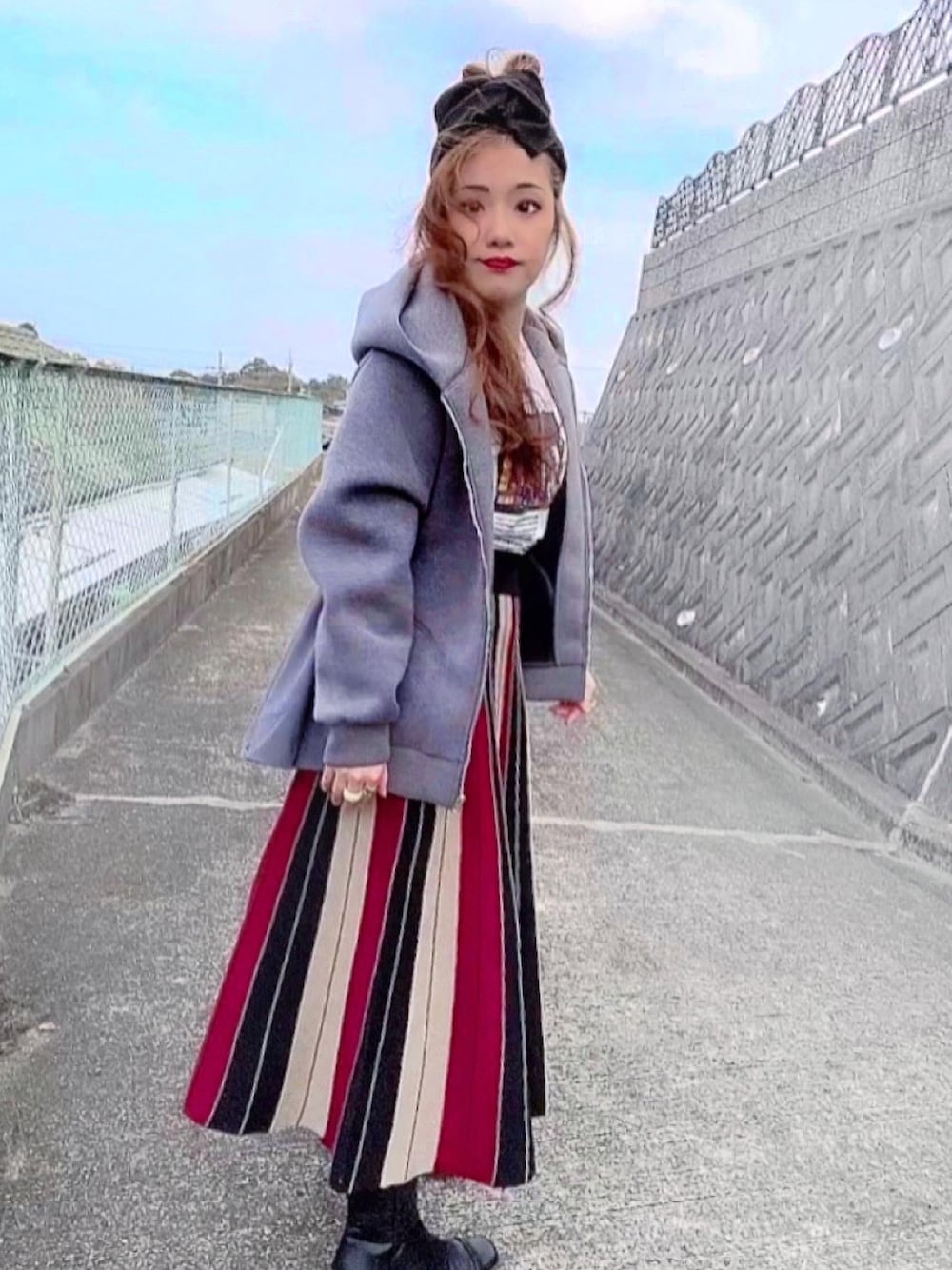 レッド系のスカート、グレー系のパーカー、ブラック系のヘアバンドを着用したレディースの秋コーディネートの1枚目の写真