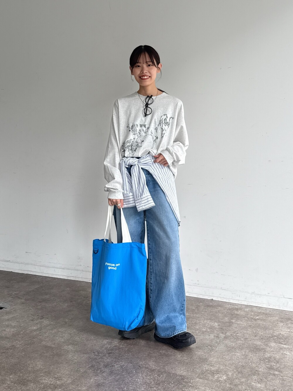 グレー系のTシャツ/カットソー、ホワイト系のシャツ/ブラウス、ブルー系のデニムパンツを着用したレディースの春コーディネートの1枚目の写真