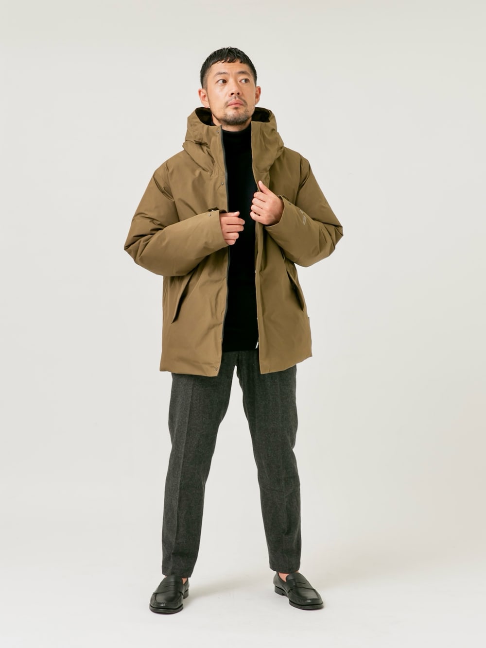 ブラウン系のダウンジャケット/コート、ブラック系のニット/セーター、グレー系のスラックスを着用したメンズの秋コーディネートの1枚目の写真