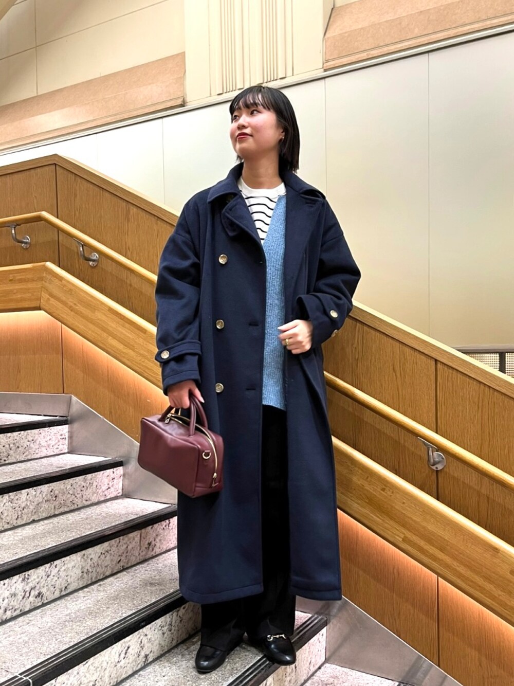 ブルー系のステンカラーコート、ホワイト系のTシャツ/カットソー、ブラック系のローファーを着用したレディースの秋コーディネートの1枚目の写真