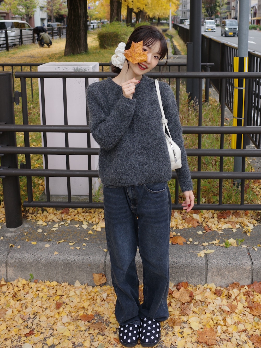 グレー系のニット/セーター、ブルー系のデニムパンツ、ホワイト系のショルダーバッグを着用したレディースの冬コーディネートの1枚目の写真