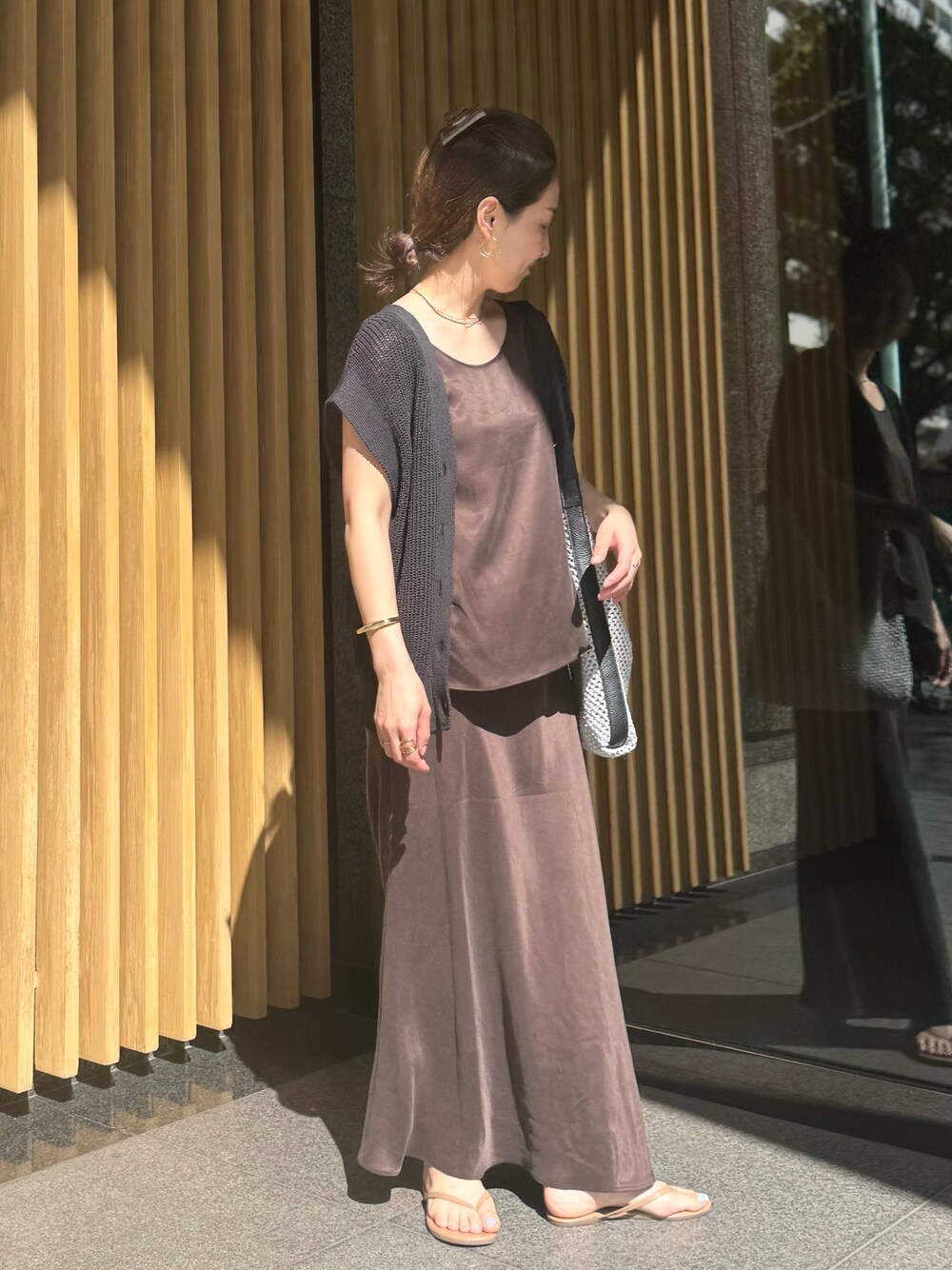 ブラウン系のスカート、ブラック系のベスト、グレー系のショルダーバッグを着用したレディースの夏コーディネートの1枚目の写真