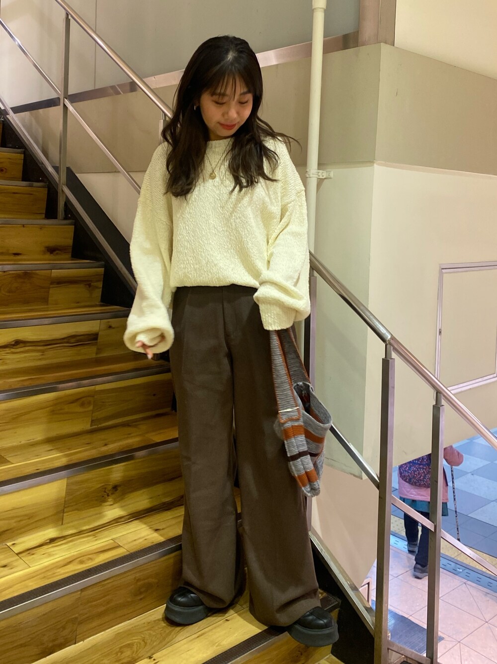 ホワイト系のニット/セーター、ブラウン系のその他パンツ、グレー系のハンドバッグを着用したレディースの冬コーディネートの1枚目の写真