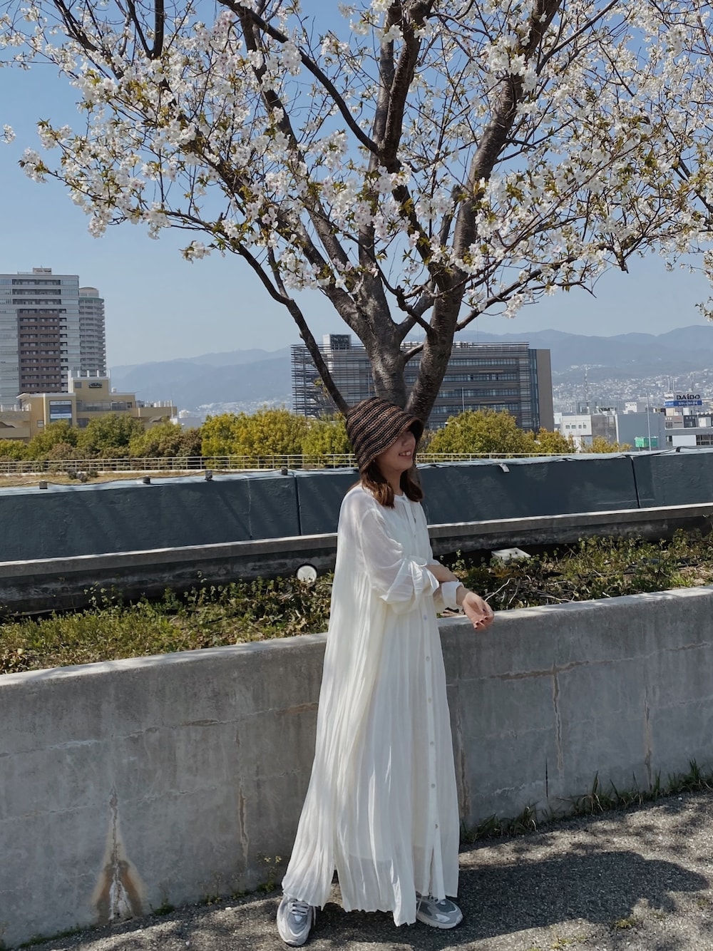 ホワイト系のワンピース、ブラウン系のハットを着用したレディースの春コーディネートの1枚目の写真