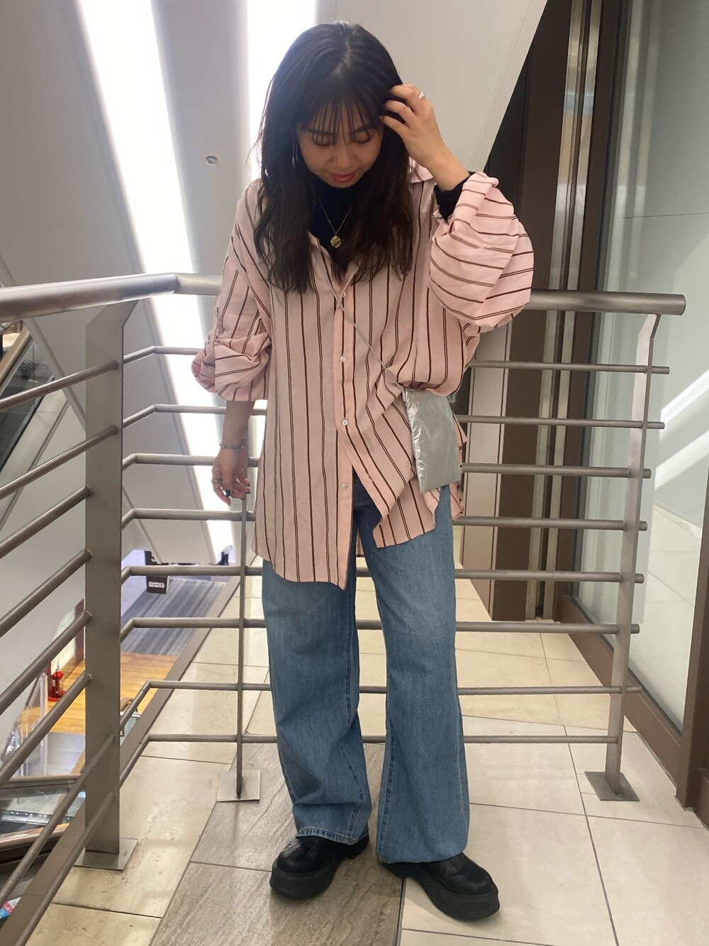 ピンク系のシャツ/ブラウス、ブルー系のデニムパンツ、シルバー系のショルダーバッグを着用したレディースの冬コーディネートの1枚目の写真