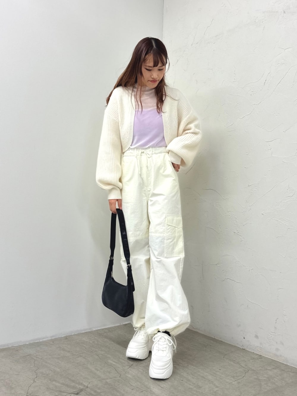 ホワイト系のスニーカー、ホワイト系のカーゴパンツ、ブラック系のショルダーバッグを着用したレディースの冬コーディネートの1枚目の写真
