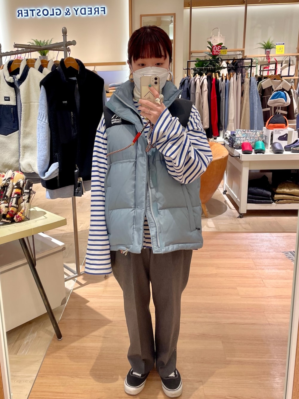 ブルー系のダウンベスト、ホワイト系のTシャツ/カットソーを着用したレディースの冬コーディネートの1枚目の写真