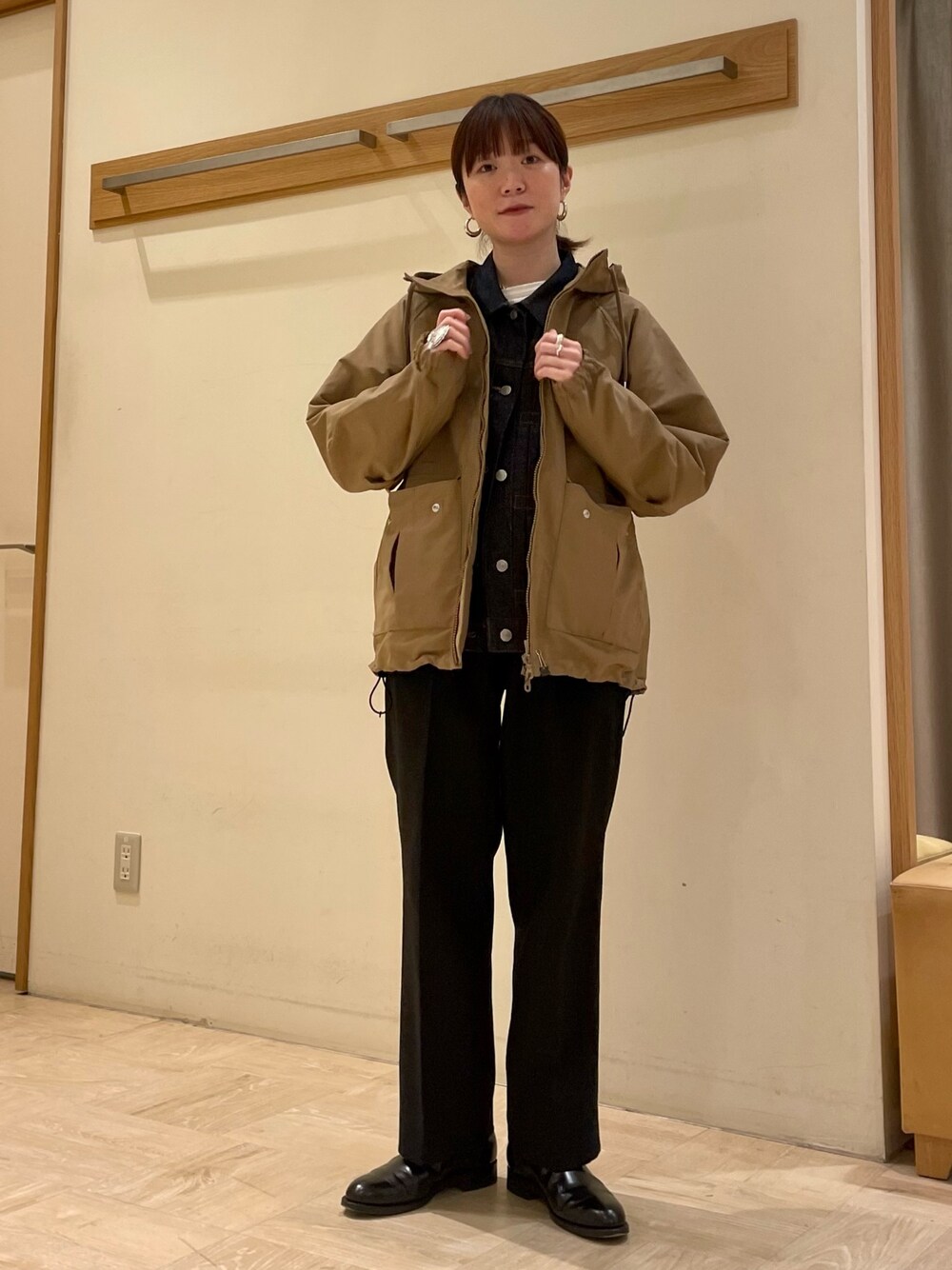 ベージュ系のブルゾン、ブルー系のデニムジャケット、ブラック系のブーツを着用したレディースの冬コーディネートの1枚目の写真