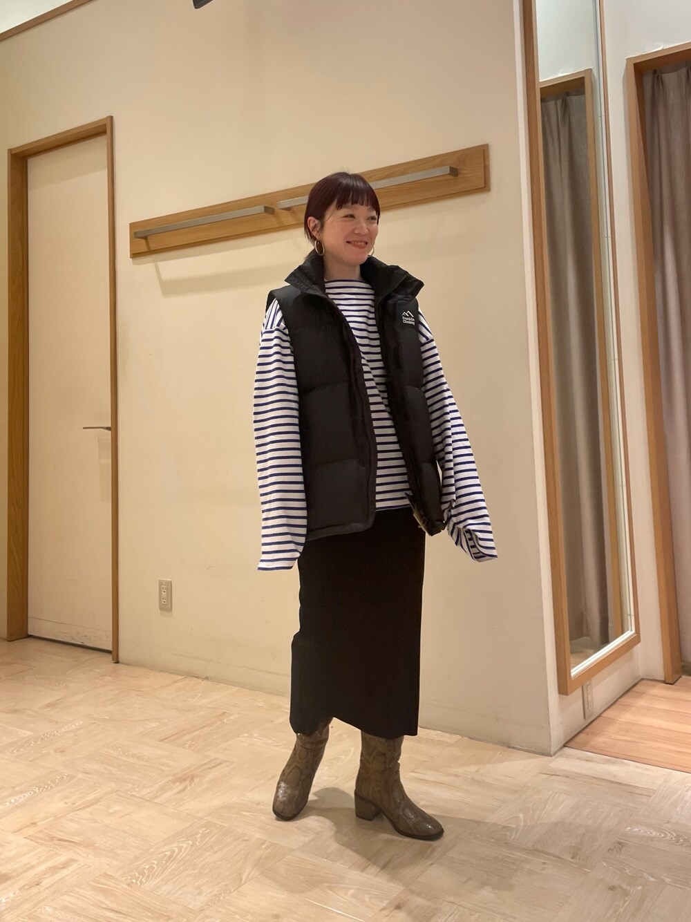 ベージュ系のブーツ、ブラック系のスカート、ホワイト系のTシャツ/カットソーを着用したレディースの冬コーディネートの1枚目の写真