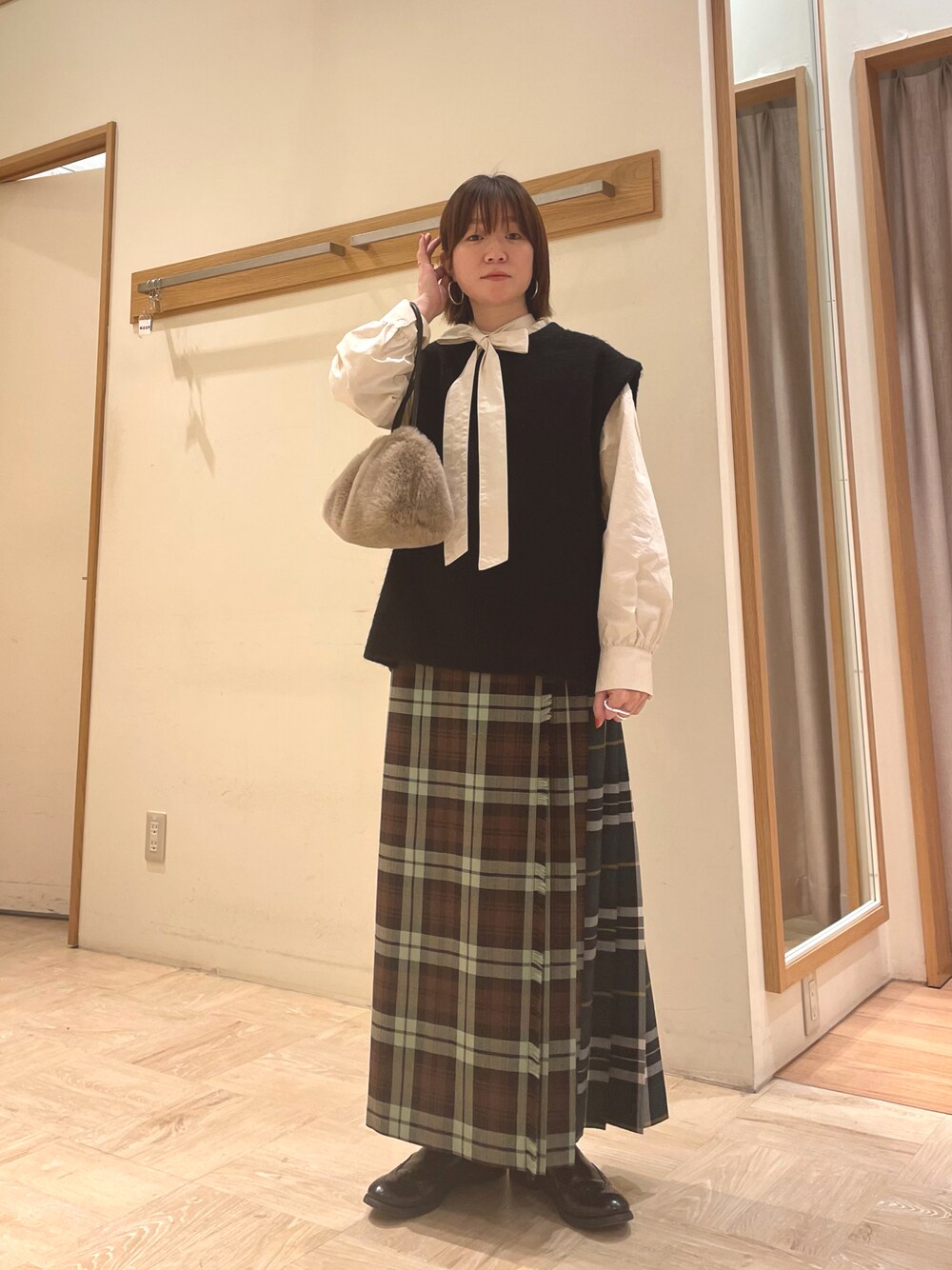 ホワイト系のシャツ/ブラウス、ブラック系のベスト、ベージュ系のショルダーバッグを着用したレディースの冬コーディネートの1枚目の写真