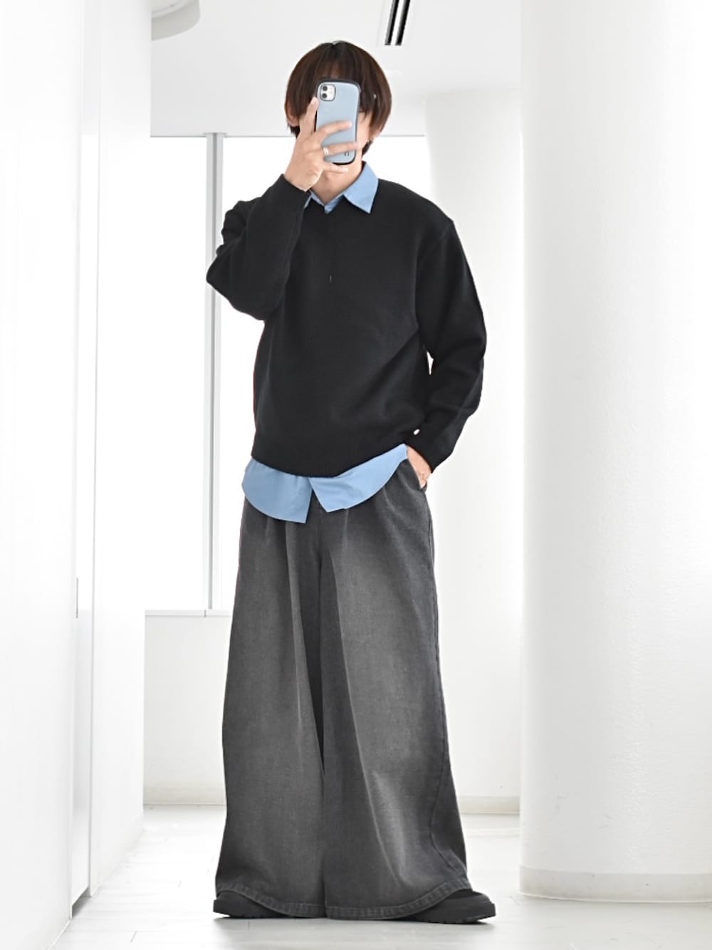 ブラック系のデニムパンツ、ブラック系のニット/セーター、ブルー系のシャツ/ブラウスを着用したメンズの冬コーディネートの1枚目の写真