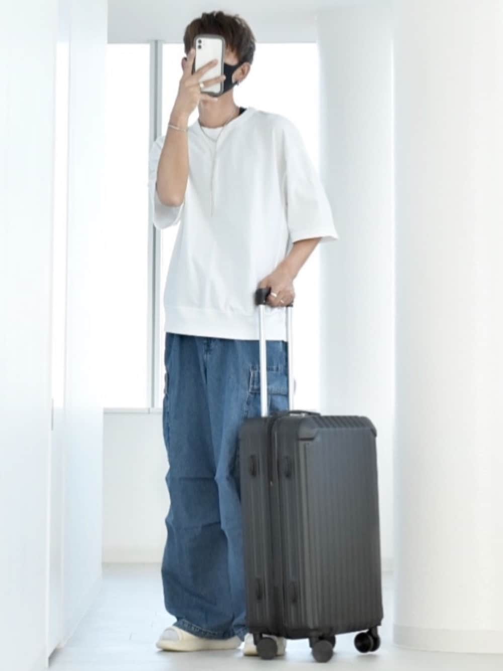 ブラック系のスーツケース/キャリーバッグ、ホワイト系のTシャツ/カットソー、ブルー系のカーゴパンツを着用したメンズの夏コーディネートの1枚目の写真