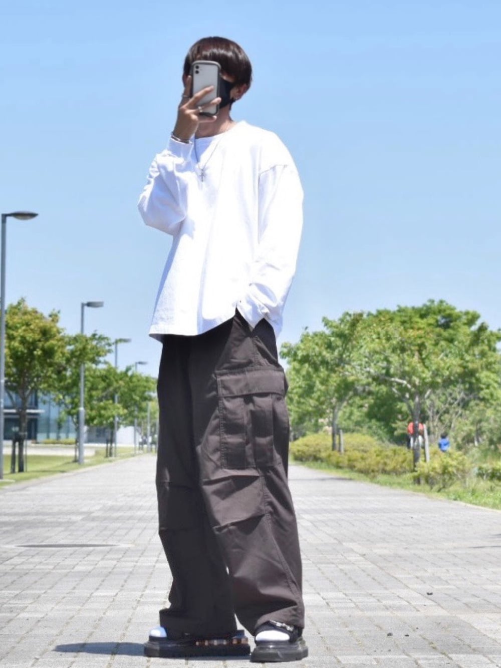 ホワイト系のTシャツ/カットソー、ブラウン系のカーゴパンツ、ブラック系のサンダルを着用したメンズの春コーディネートの1枚目の写真