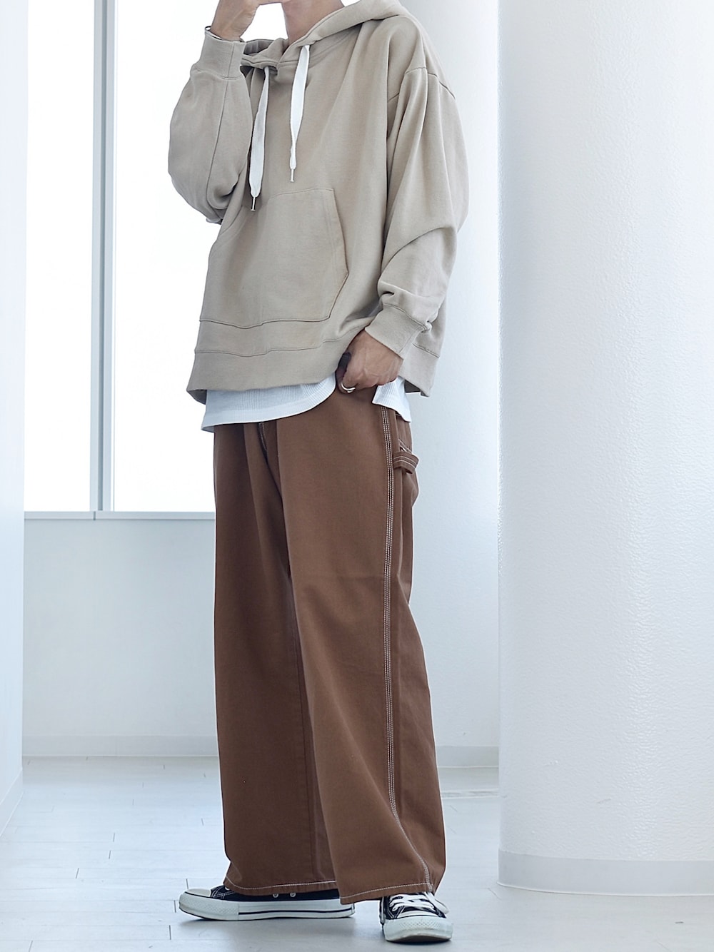 ブラウン系のデニムパンツ、ベージュ系のパーカー、ホワイト系のタンクトップを着用したメンズの秋コーディネートの1枚目の写真