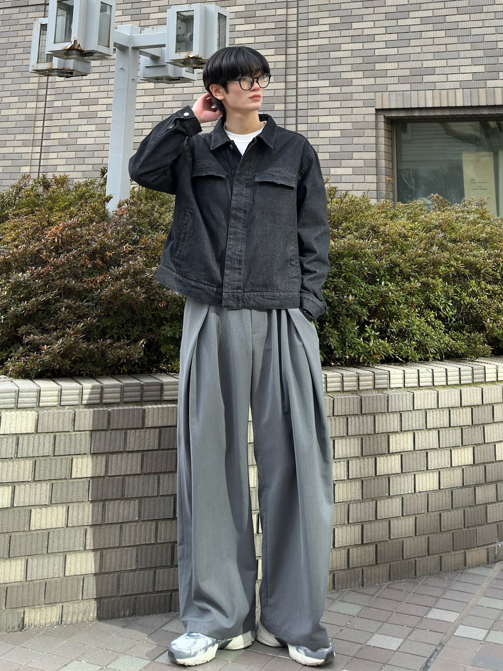 ブラック系のデニムジャケット、グレー系のスラックス、グレー系のスニーカーを着用したメンズの春コーディネートの1枚目の写真