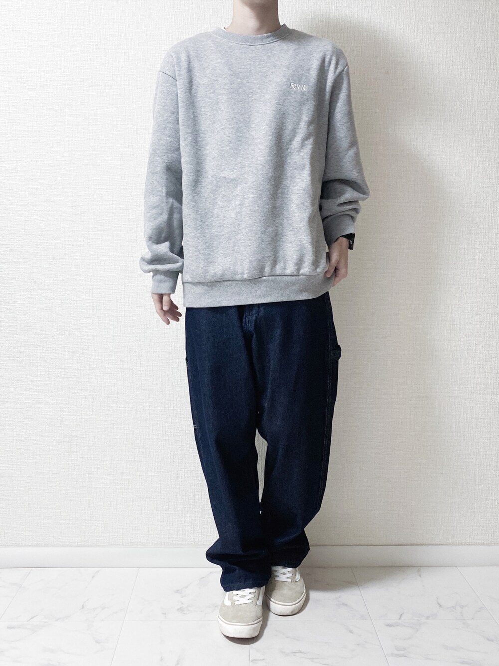 ブルー系のデニムパンツ、グレー系のスウェット、ベージュ系のスニーカーを着用したメンズの秋コーディネートの1枚目の写真