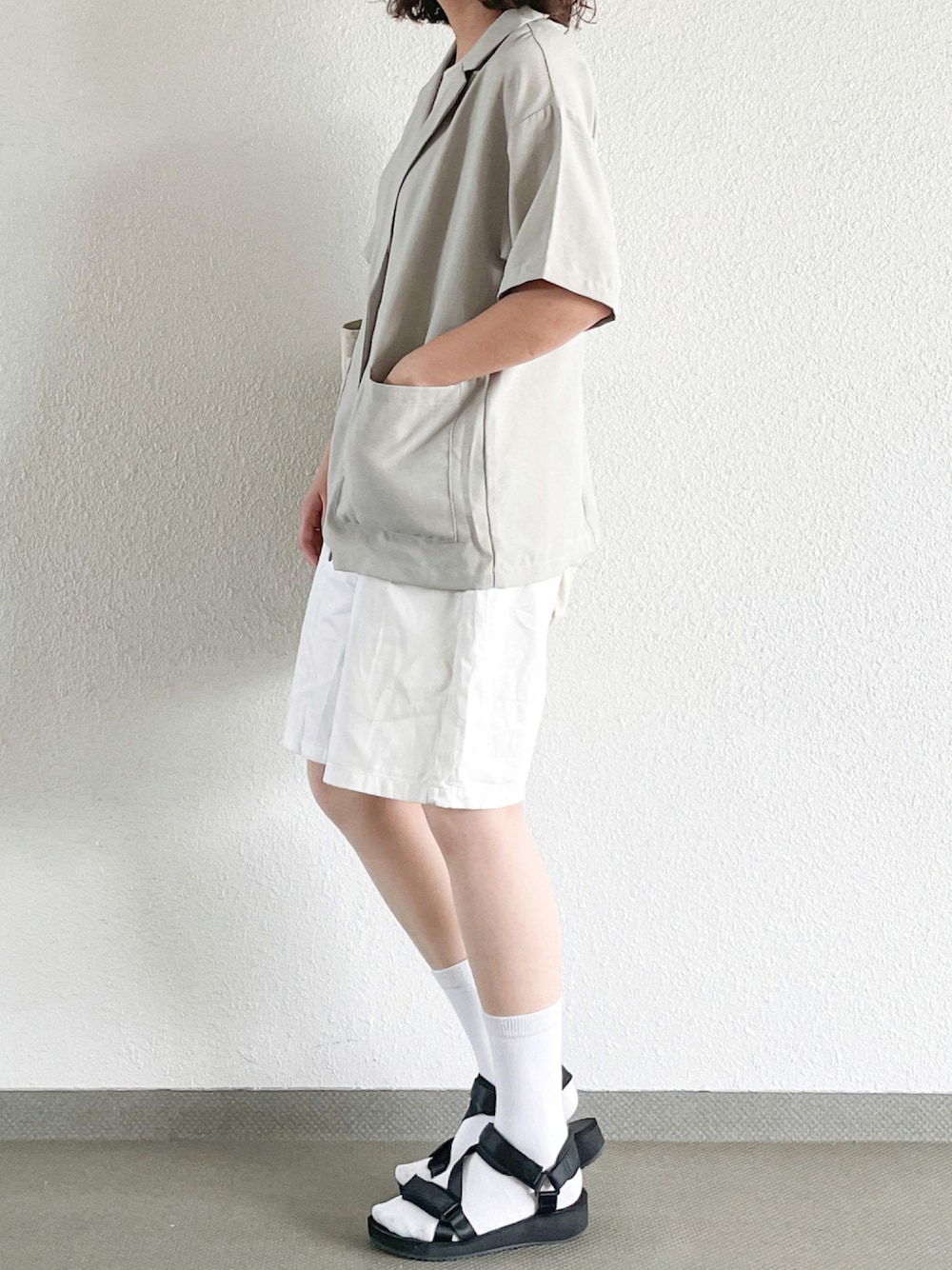 ホワイト系のジャケット/アウター、ホワイト系のパンツ、ブラック系のサンダルを着用したレディースの秋コーディネートの1枚目の写真