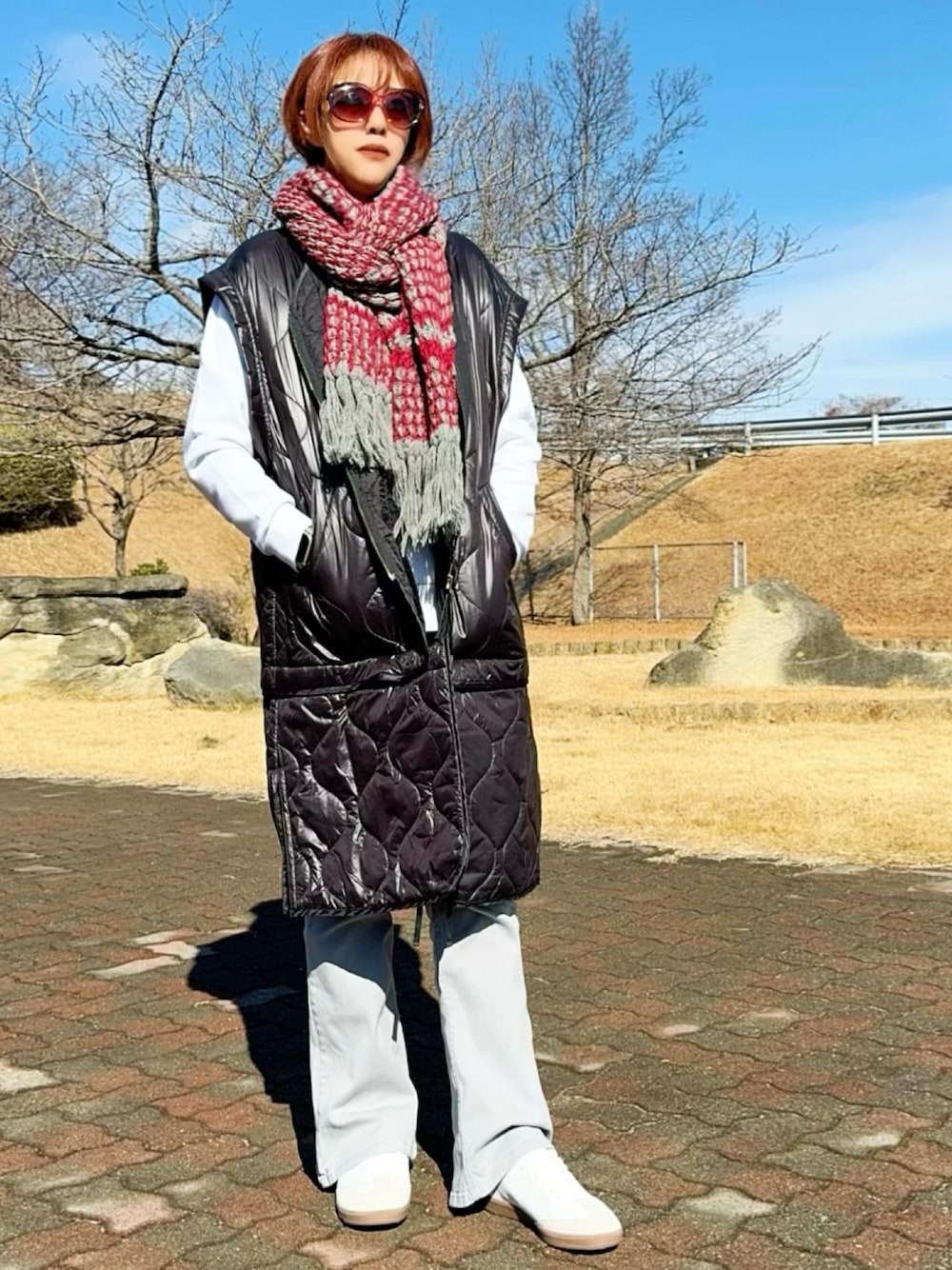 ブラック系のベスト、ホワイト系のスウェット、グレー系のデニムパンツを着用したレディースの冬コーディネートの1枚目の写真