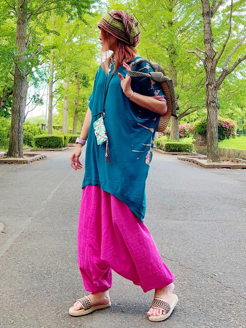 ブラウン系のショルダーバッグ、ベージュ系のシューズ、ブルー系のチュニックを着用したレディースの夏コーディネートの1枚目の写真