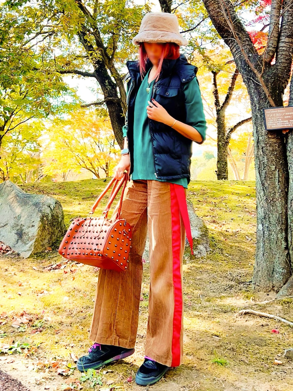 ブラウン系のボストンバッグ、ブラック系のスニーカー、グリーン系のニット/セーターを着用したレディースの秋コーディネートの1枚目の写真