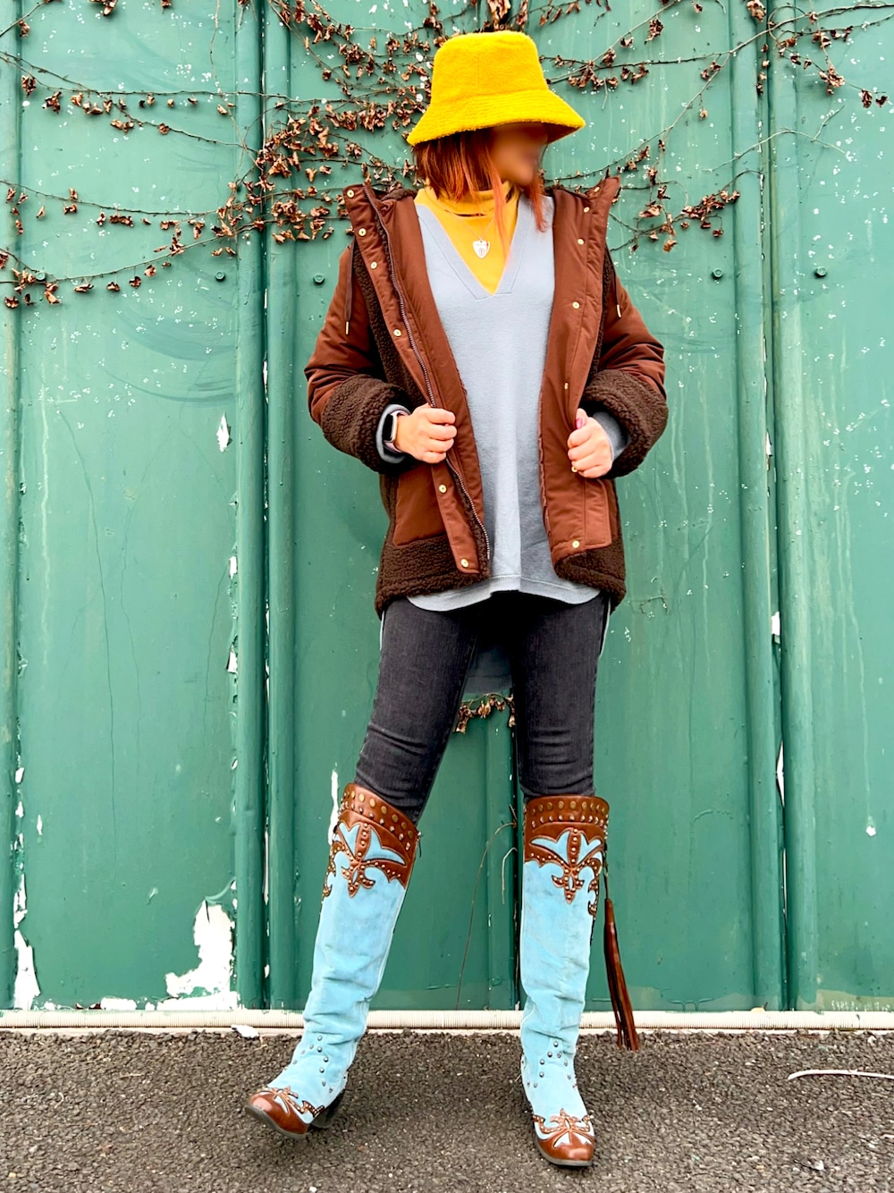 ブラウン系のダウンジャケット/コート、ブルー系のニット/セーター、イエロー系のTシャツ/カットソーを着用したレディースの冬コーディネートの1枚目の写真