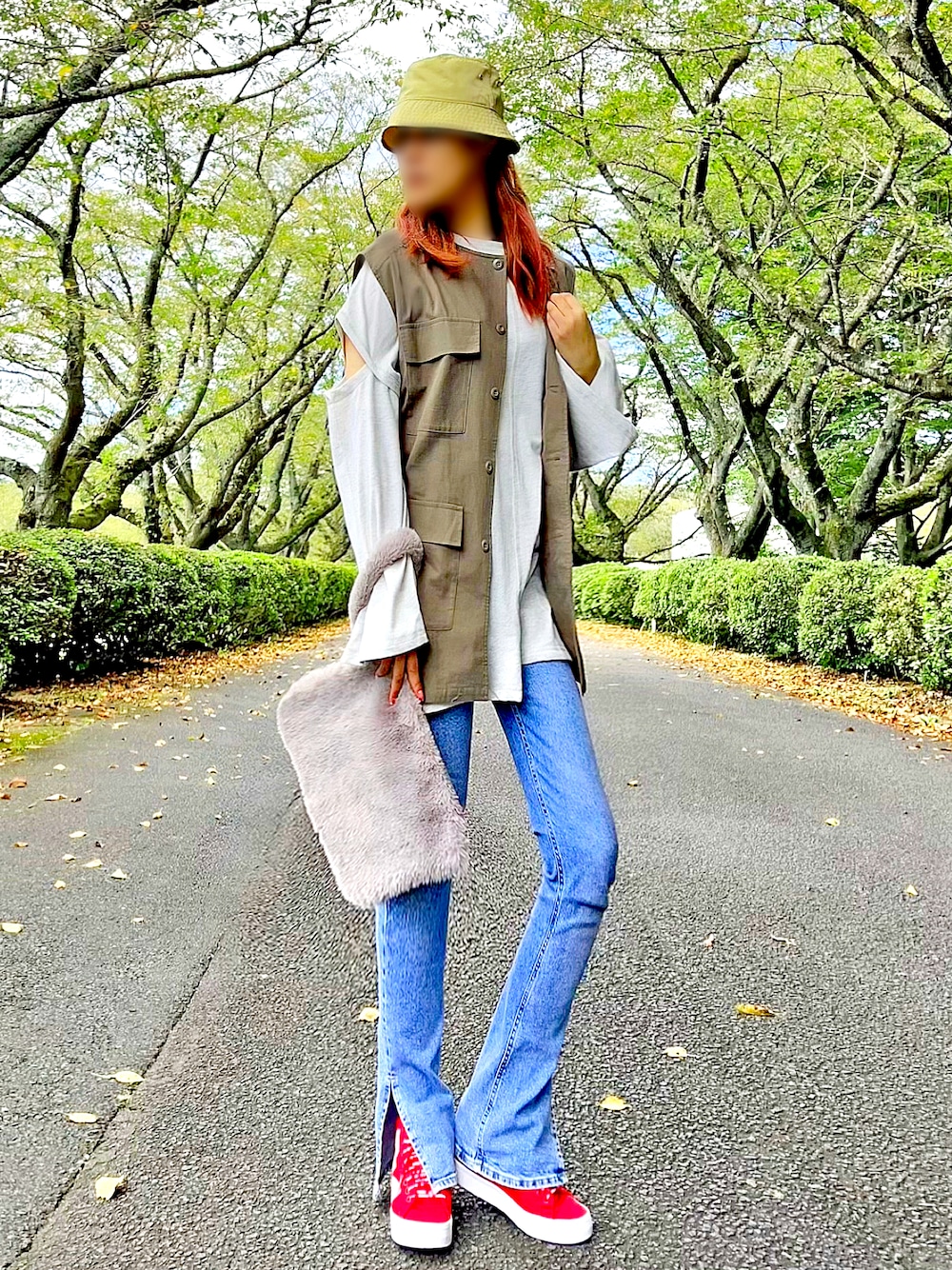 グリーン系のベスト、グレー系のTシャツ/カットソー、ブルー系のデニムパンツを着用したレディースの秋コーディネートの1枚目の写真