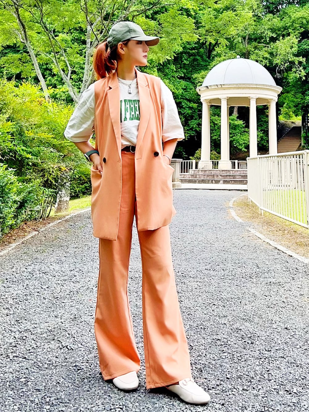 オレンジ系のスーツベスト、オレンジ系のスーツパンツ、ホワイト系のトップスを着用したレディースの夏コーディネートの1枚目の写真