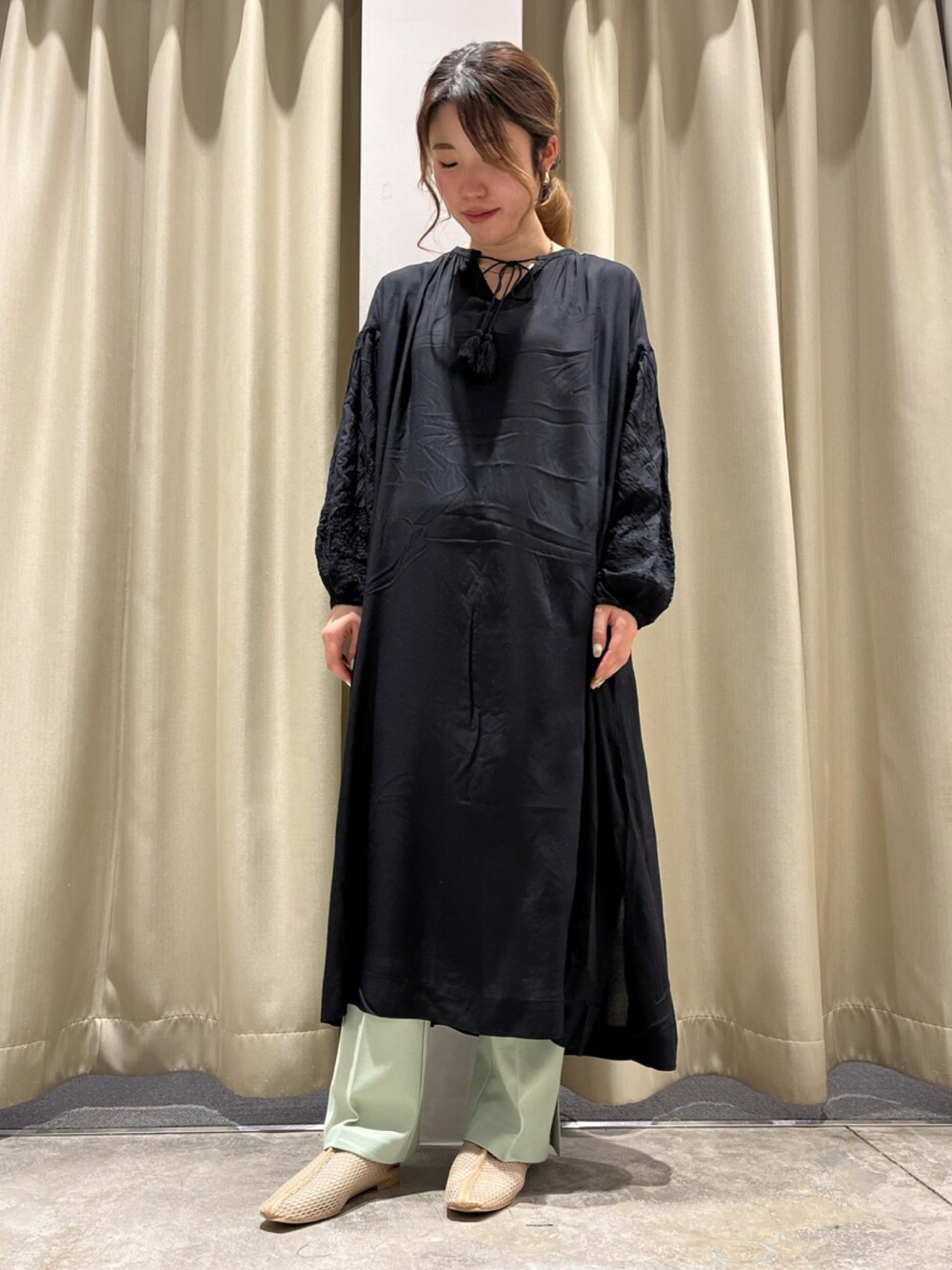 ベージュ系のパンプス、グリーン系のその他パンツ、ブラック系のワンピースを着用したレディースの春コーディネートの1枚目の写真