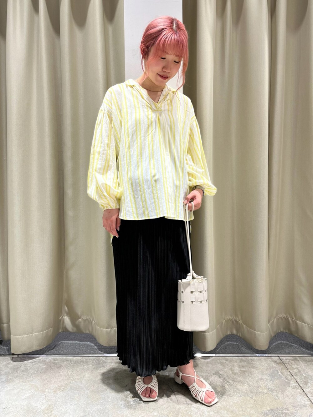 ホワイト系のショルダーバッグ、ブラック系のスカート、イエロー系のシャツ/ブラウスを着用したレディースの春コーディネートの1枚目の写真
