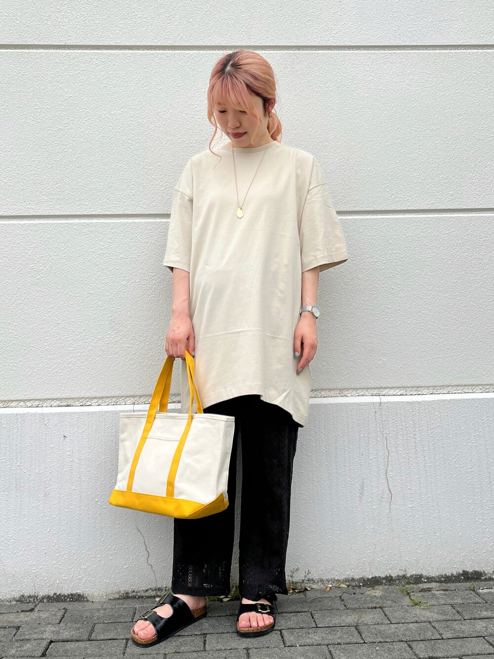 イエロー系のトートバッグ、ベージュ系のTシャツ/カットソー、ブラック系のその他パンツを着用したレディースの春コーディネートの1枚目の写真