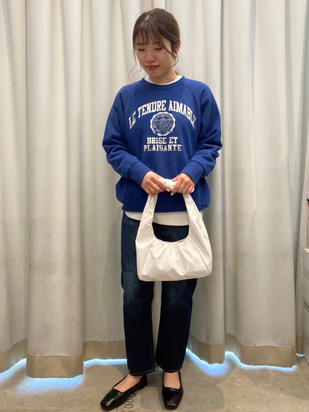 ホワイト系のハンドバッグ、ホワイト系のTシャツ/カットソー、ブルー系のデニムパンツを着用したレディースの冬コーディネートの1枚目の写真