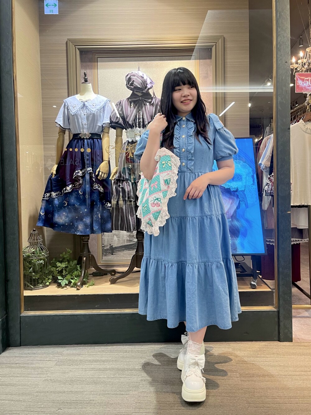 ブルー系のワンピース、グリーン系のトートバッグ、ホワイト系のスニーカーを着用したレディースの夏コーディネートの1枚目の写真