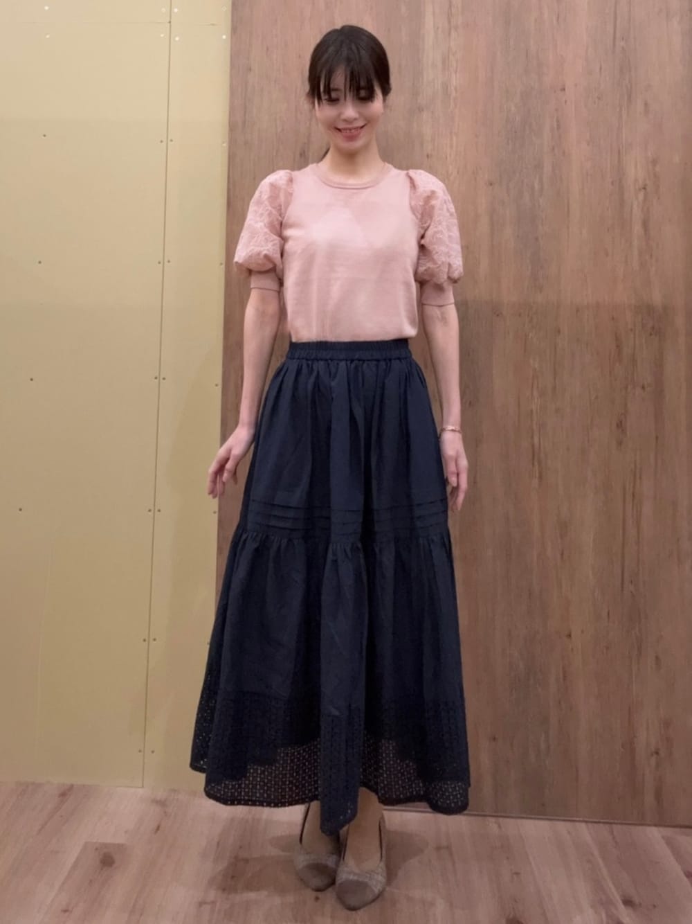 ブラウン系のパンプス、ピンク系のニット/セーター、ブルー系のスカートを着用したレディースの春コーディネートの1枚目の写真
