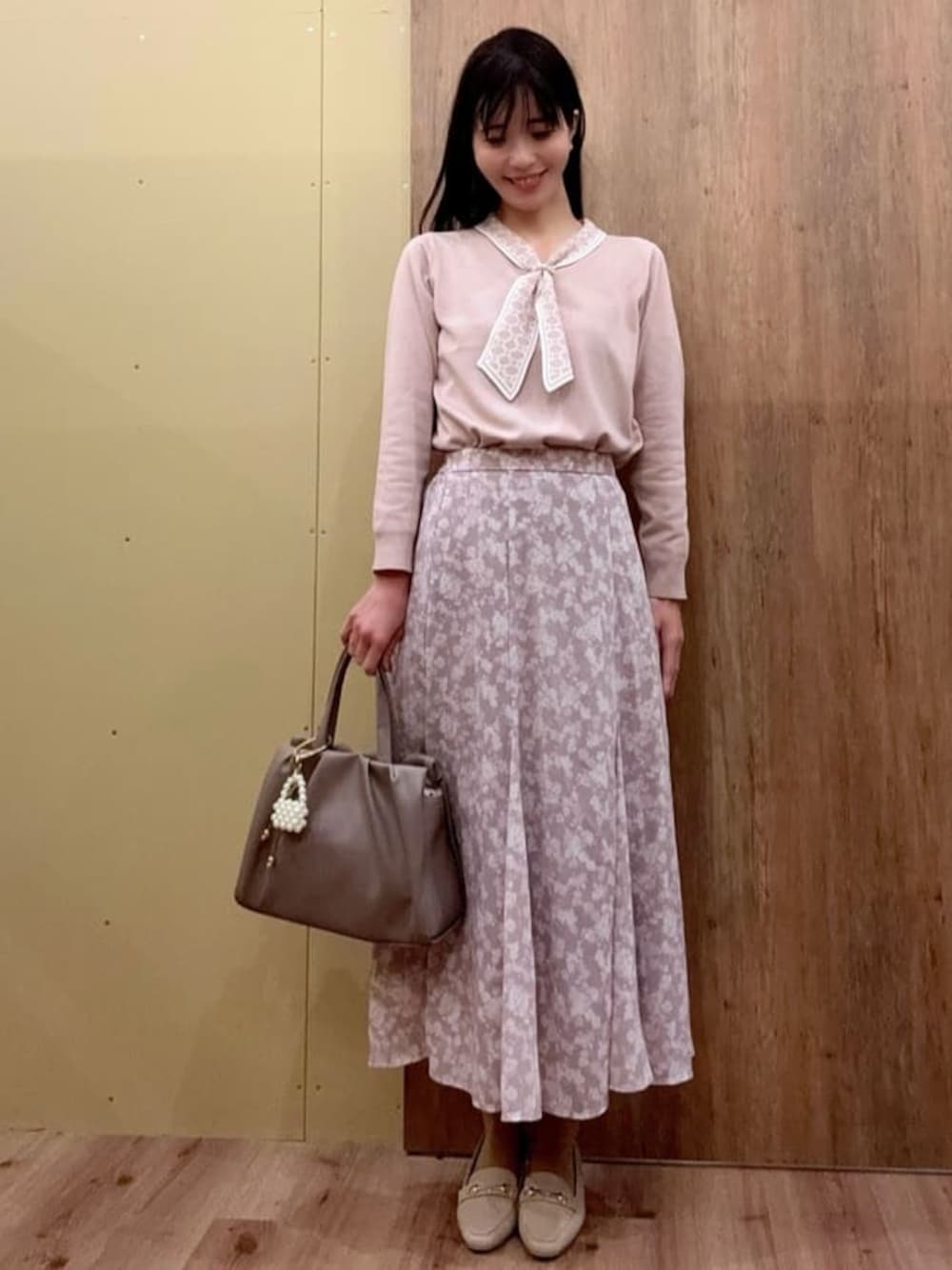 ベージュ系のパンプス、ブラウン系のトートバッグ、ピンク系のスカートを着用したレディースの春コーディネートの1枚目の写真