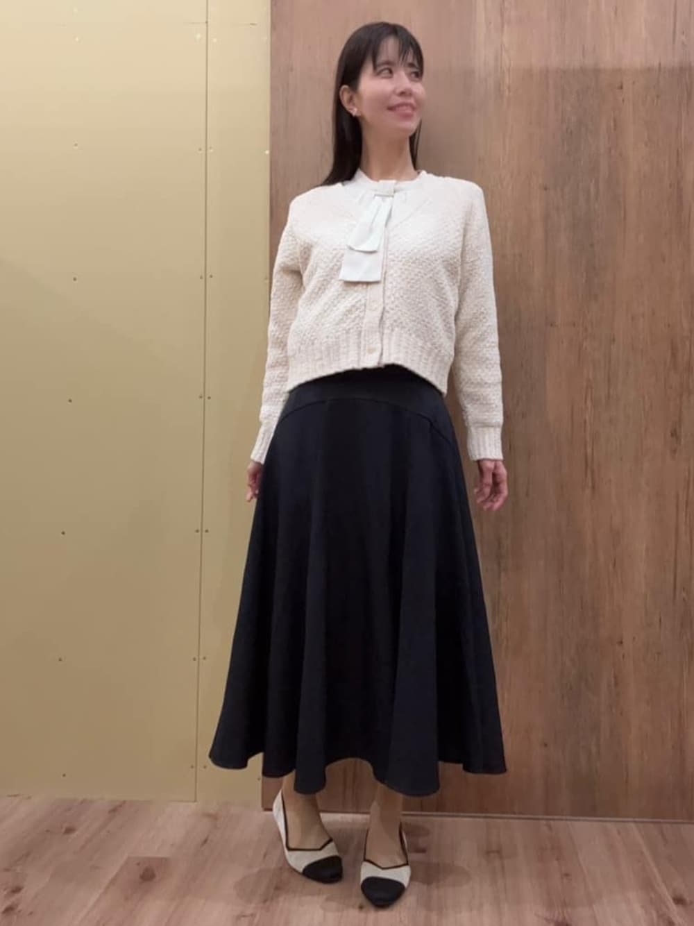 ホワイト系のカーディガン/ボレロ、ホワイト系のシャツ/ブラウス、ブルー系のスカートを着用したレディースの冬コーディネートの1枚目の写真