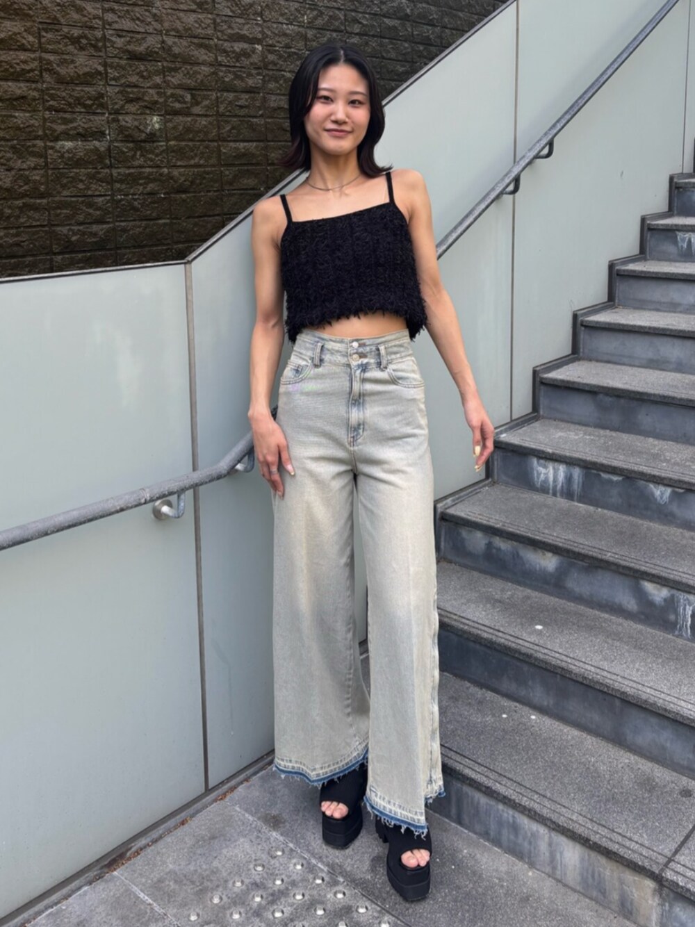 ブルー系のデニムパンツ、ブラック系のキャミソール、ブラック系のブーツを着用したレディースの春コーディネートの1枚目の写真