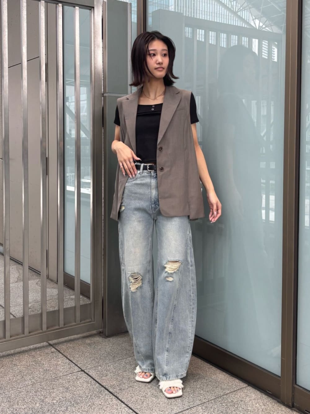 ホワイト系のサンダル、ブラック系のTシャツ/カットソー、ブラウン系のベストを着用したレディースの夏コーディネートの1枚目の写真