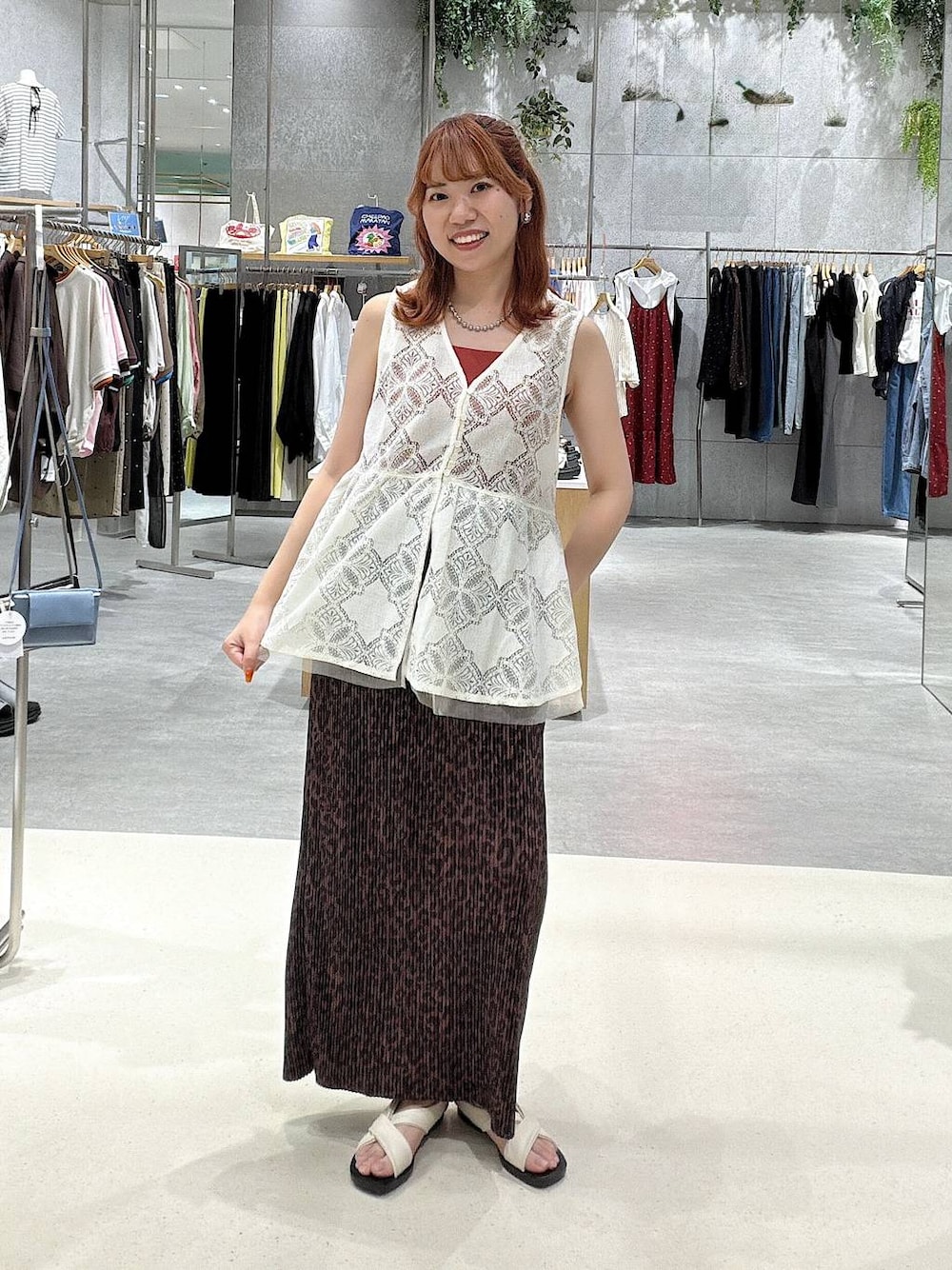 レッド系のキャミソール、ブラウン系のスカート、ホワイト系のサンダルを着用したレディースの夏コーディネートの1枚目の写真