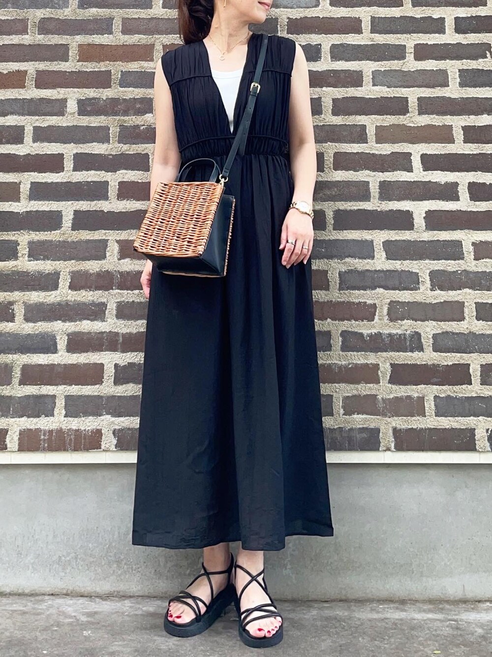 ブラック系のワンピース、ブラック系のサンダル、ブラウン系のかごバッグを着用したレディースの夏コーディネートの1枚目の写真