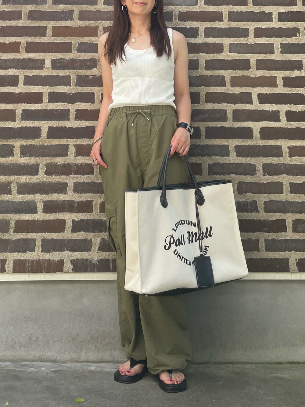 グリーン系のカーゴパンツ、ブラック系のバッグ、ブラック系のサンダルを着用したレディースの夏コーディネートの1枚目の写真