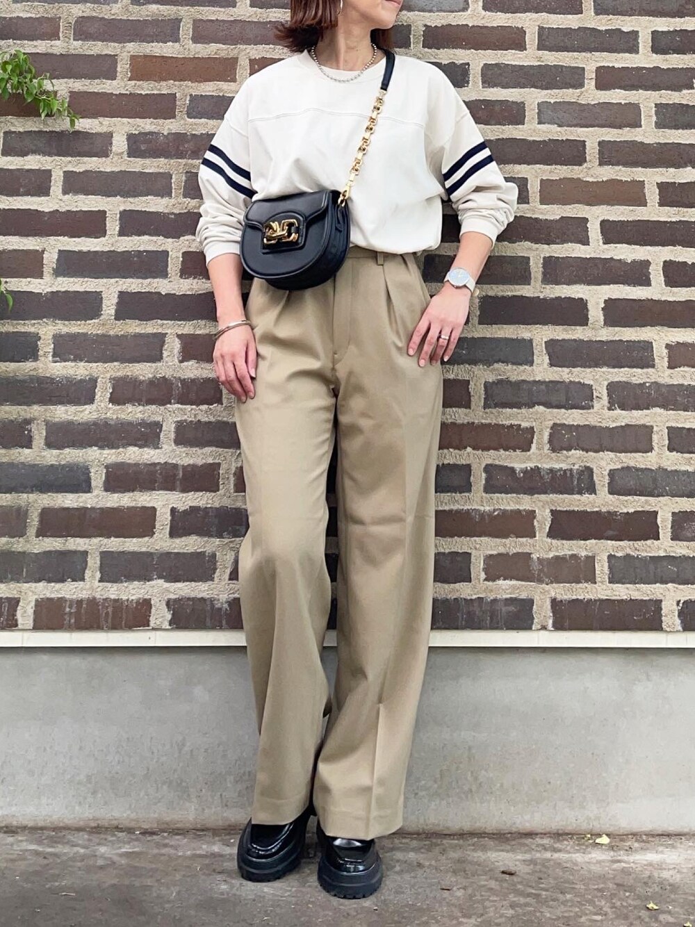 ベージュ系のパンツ、ブラック系のローファー、ブラック系のショルダーバッグを着用したレディースの秋コーディネートの1枚目の写真