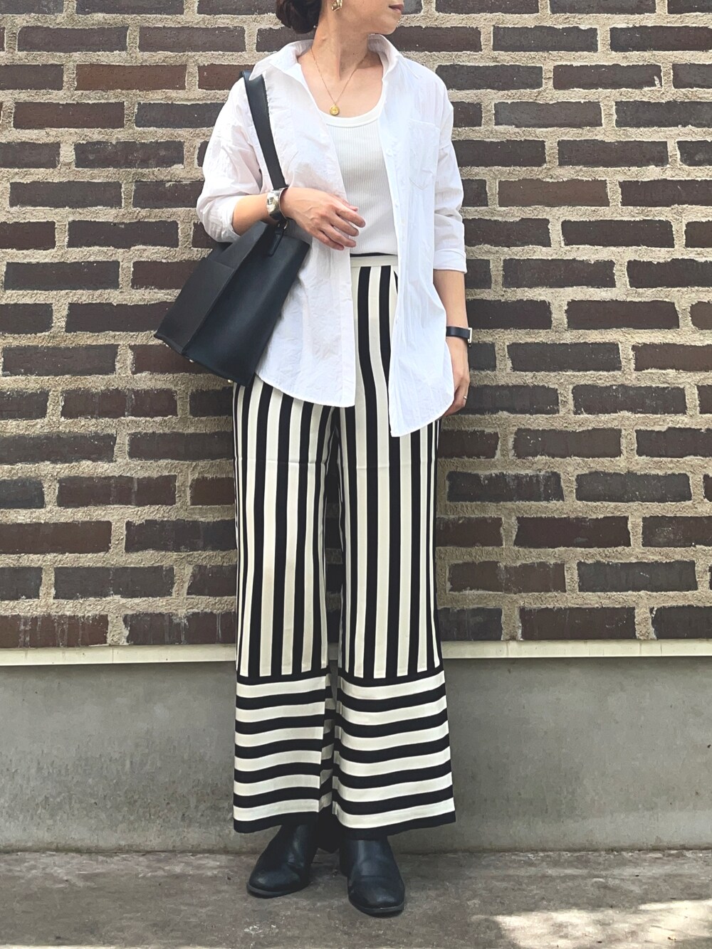 ブラック系のその他パンツ、ブラック系のブーツ、シルバー系のアナログ腕時計を着用したレディースの秋コーディネートの1枚目の写真