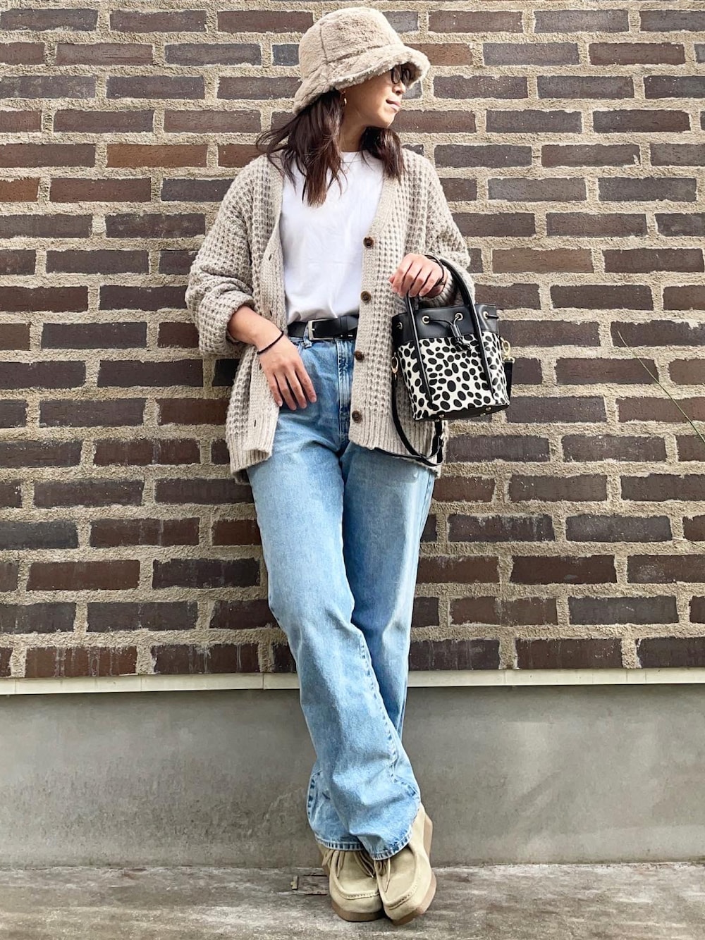 ブラック系のショルダーバッグ、ベージュ系のモカシン/デッキシューズ、ブルー系のデニムパンツを着用したレディースの秋コーディネートの1枚目の写真