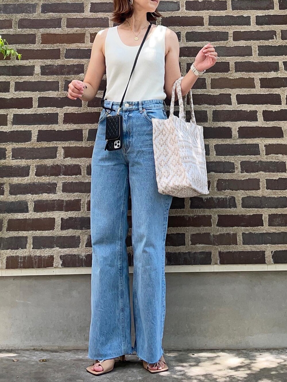 ブルー系のデニムパンツ、ベージュ系のサンダル、その他のトートバッグを着用したレディースの夏コーディネートの1枚目の写真